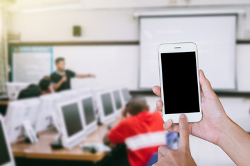 Wall Mural - Hands woman are holding touch screen smart phone,tablet on blurred classroom computer with student and teacher background.
