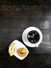 Wall Mural - One small croissant with vanilla cream and cheese pastry with chocolate pieces served in white plate with black filtered coffee for a traditional greek breakfast