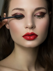 Wall Mural - Close-up of female green eye with burgundy thick eyeliner. Mascara brush colors extra long eyelashes. Thick beautiful eyebrows and red lips. Clean smooth skin. Cosmetology and spa