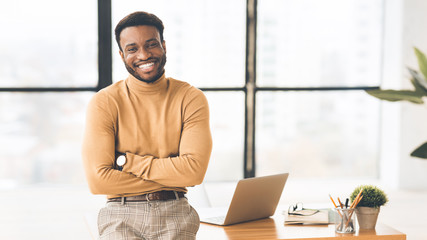 Poster - African businessman sitting on desk looking at camera