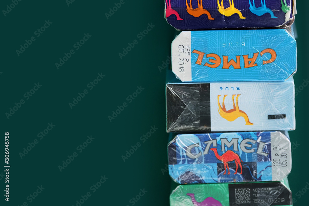 camel cigarettes colors Moscow, Russia - December, 2019: Many packs of cigarettes from different  countries of the same brand, Camel. Camel color limited edition, blue  limited art on dark green background Stock Photo