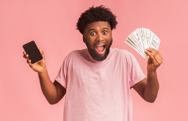 Thrilled guy holding phone and showing bunch of money