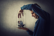Conceptual Scene, Scared Tiny Boy Trapped Inside A Glass Jar Held In Hand By A Scary Giant. Surreal Nightmare, Child Adoption Through The Eyes Of A Teen. Helpless Captive Kid Victim Of Family Abuse.