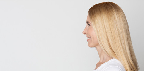 Wall Mural - Happy middle-aged woman looking at free space, gray background