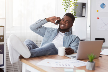 Poster - Confident young businessman resting at workplace with his legs on table