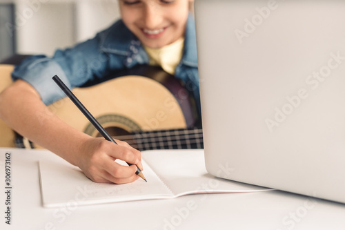 Fotografía Kid making notes during online music lesson