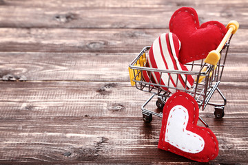 Poster - Shopping cart with fabric hearts on brown wooden table