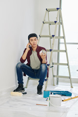 Poster - Young Asian man ordering white paint on the phone when reconstructing room in his apartment