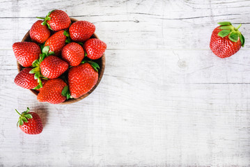 Wall Mural - Ripe strawberries forest fruits in wooden bowl on white table. Fresh strawberry top view.