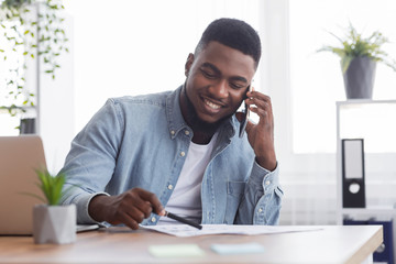 Poster - African businessman talking with companion on phone and checking financial reports