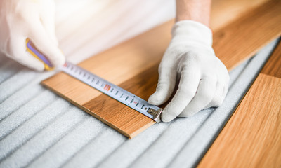 Wall Mural - Detail of male hands with in white gloves measuring tape and new laminated wooden floor board.