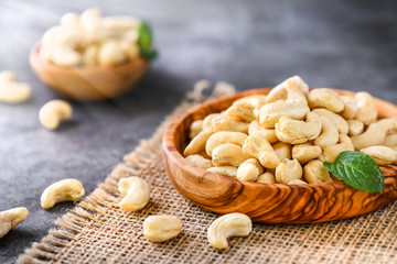 Cashew nuts in olive wooden bowl on dark stone table. Delicacies nut on black background.