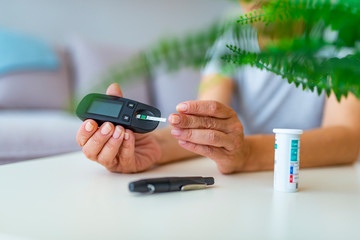 Wall Mural - Woman using lancelet on finger. Close up woman hands using lancet on finger to check blood sugar level by Glucose meter, Healthcare Medical Check up, Medicine, diabetes, hyperglycemia concept