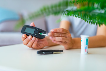 Wall Mural - Test Blood Glucose For Diabetes in Pregnant Woman With Glucometer. One red drop of blood on the finger ready to measure sugar level. Close up of male finger with blood drop and test stripe