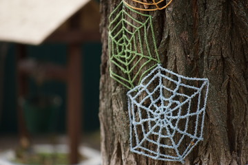 Blue and green knitted cobwebs on a tree trunk close-up.