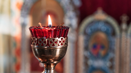 Wall Mural - Orthodox Church Lamp with lit Candle and Red Glass on the icon background.