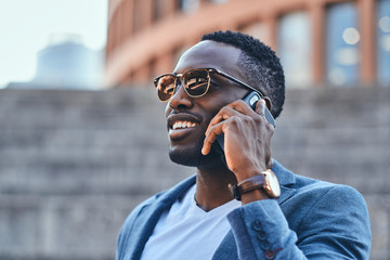 Wall Mural - Attractive american businessman is talking by mobile phone in the street.