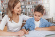© Ihor - Adorable young boy doing his homework with mom at the library