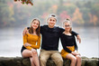 © Anna - Three teenagers friends, sisters and brother  sitting on a rocky wall, with the view on lake on fall Family photography