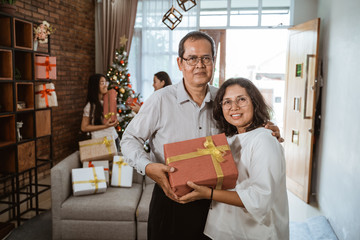 mature couple with gift box on christmas day at home