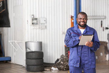 Wall Mural - African-American mechanic with tablet computer in car service center