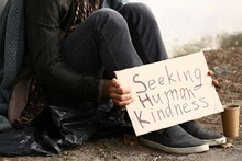 Poor Homeless Man Holding Cardboard With Text SEEKING HUMAN KINDNESS Outdoors