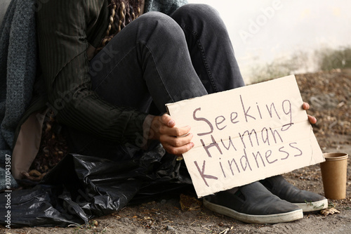 Fotomural Poor homeless man holding cardboard with text SEEKING HUMAN KINDNESS outdoors