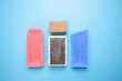 Flat lay of used red and blue warm and cold ski wax blocks, brush and cork, styled on blue background