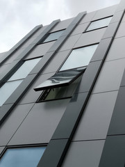 Poster - Close-up photo of windows and wall panels. Fragment of industrial building exterior with ajar window. Generic elements of modern office architecture. Regular linear pattern of parallel lines.