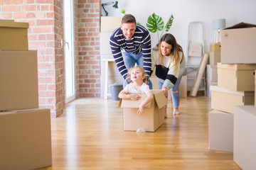 Beautiful famiily, kid playing with his parents riding cardboard fanny box at new home