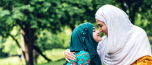 Portrait Of Happy Lovely Family Arabic Muslim Mother And Little Muslim Girls Child With Hijab Dress Smiling And Having Fun Hugging And Kissing Together In Summer Park