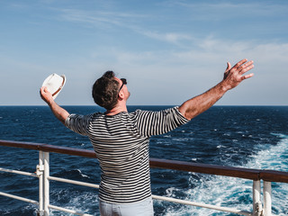 Smiling man on the empty deck of a cruise liner on the background of sea waves. Top view, close-up. Concept of leisure and travel