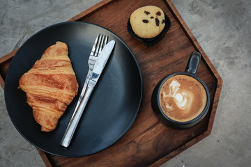 Wall Mural - A cup of coffee with latte art on top and butter  croissant