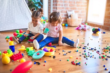 Adorable toddlers playing meals using plastic food and cutlery toy at kindergarten