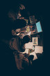 © deagreez - High angle above view vertical photo of four busy hard-working business people working overtime late evening study seminar watch notebook dark office sitting table indoors