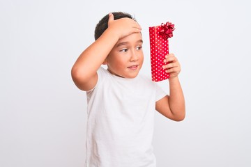 Canvas Print - Beautiful kid boy holding birthday gift standing over isolated white background stressed with hand on head, shocked with shame and surprise face, angry and frustrated. Fear and upset for mistake.