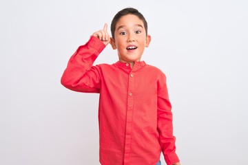 Beautiful kid boy wearing elegant red shirt standing over isolated white background pointing finger up with successful idea. Exited and happy. Number one.