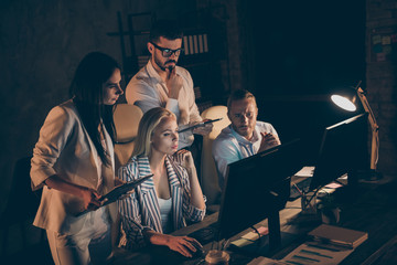 Poster - Photo of four people partners sitting chairs standing table working late night making management analysis seriously looking screen new startup project formalwear dark office indoors