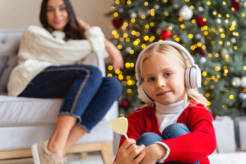 Wall Mural - Girl and her mother sitting near a Christmas tree