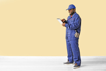 Wall Mural - African-American car mechanic with tablet computer near color wall