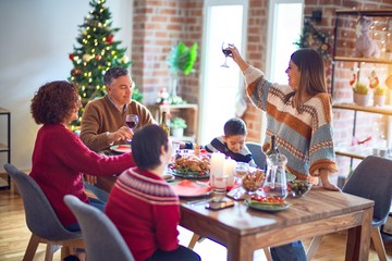 Wall Mural - Beautiful family smiling happy and confident. One of them standing holding cup of wine speaking speech celebrating christmas at home