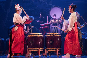 Wall Mural - Traditional Japanese performance. Group of actresses in traditional white and red kimono and fox masks drum on the stage.