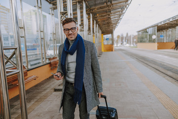 Cheerful handsome man with cellphone walking on the street