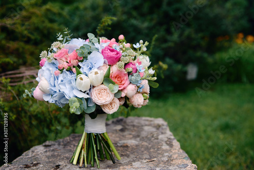 Obraz na PCV Close up of bridal bouquet of pink roses and blue hydrangea flowers on stone background outdoors, copy space. Wedding concept