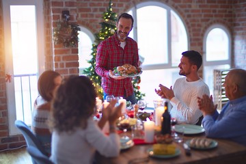 Wall Mural - Beautiful family smiling happy and confident. Showing roasted turkey and applauding celebrating Christmas at home