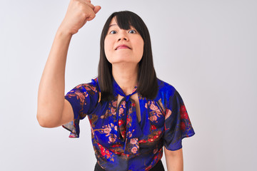 Wall Mural - Young beautiful chinese woman wearing summer floral t-shirt over isolated white background angry and mad raising fist frustrated and furious while shouting with anger. Rage and aggressive concept.