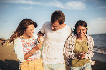 Young friends having a walk on the beach. Young people looking happy on vacation.