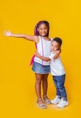 Wall Mural - Little black siblings posing together on yellow background in studio