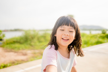 Wall Mural - Happy Little asian girl child showing front teeth with big smile, laughing and jogging in summer park in Japan : Healthy happy funny smiling face young adorable lovely female kid.Joyful portrait girl.