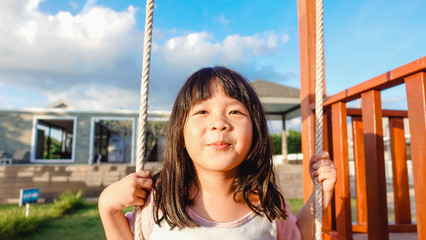 Wall Mural - 5 years old.Asian child girl playing on playground in outdoor park.Happy Little asian girl playing swing with her friends.Happy moment and good emotion.